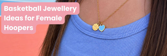 Close-up of a gold Love of the Game basketball necklace with a blue heart charm worn with a blue top, with text reading “Basketball Jewellery Ideas for Female Hoopers.” Featured image for a basketball jewellery gift guide.