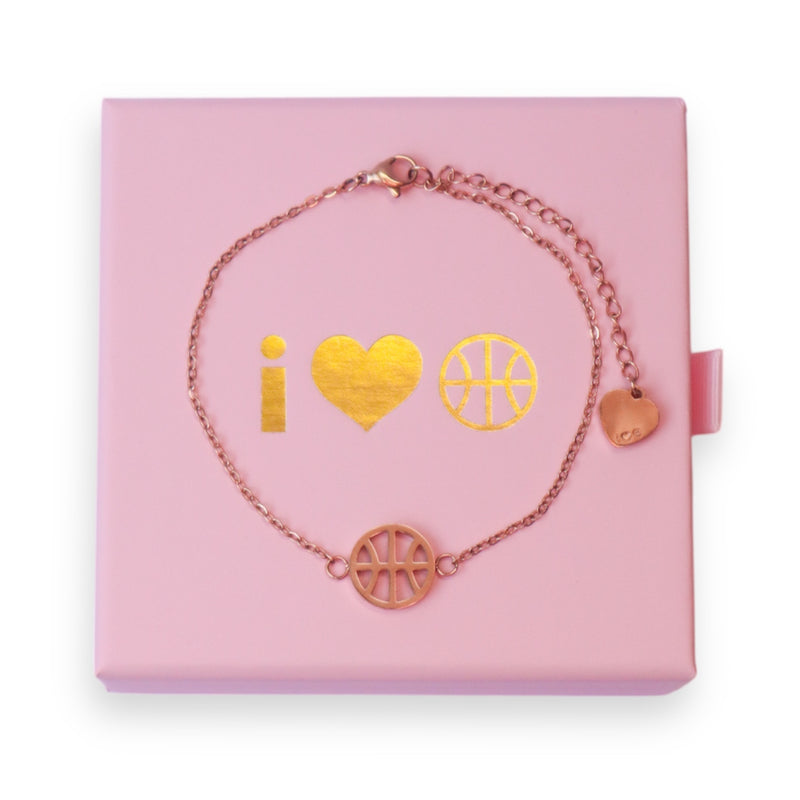 Rose gold adjustable bracelet with basketball charm and heart charm on the end of the extender chain, displayed on pink I Heart Hoops jewellery box