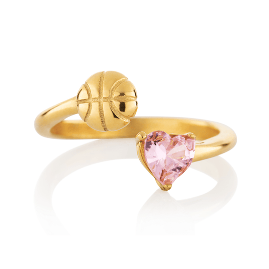 Gold Follow Through basketball ring with pink heart-shaped gemstone and basketball detail on a white background