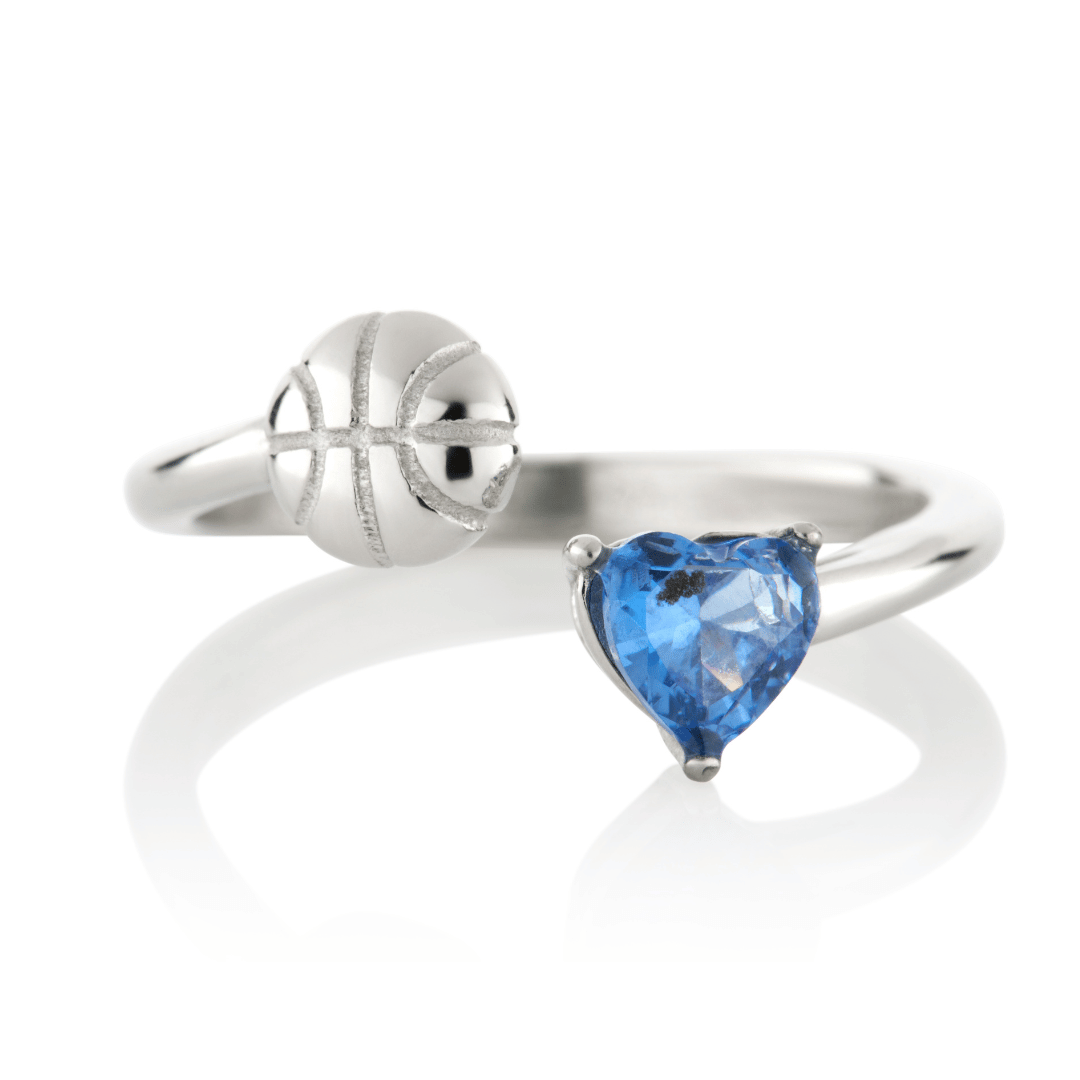Silver Follow Through basketball ring with blue heart-shaped gemstone and basketball detail on a white background