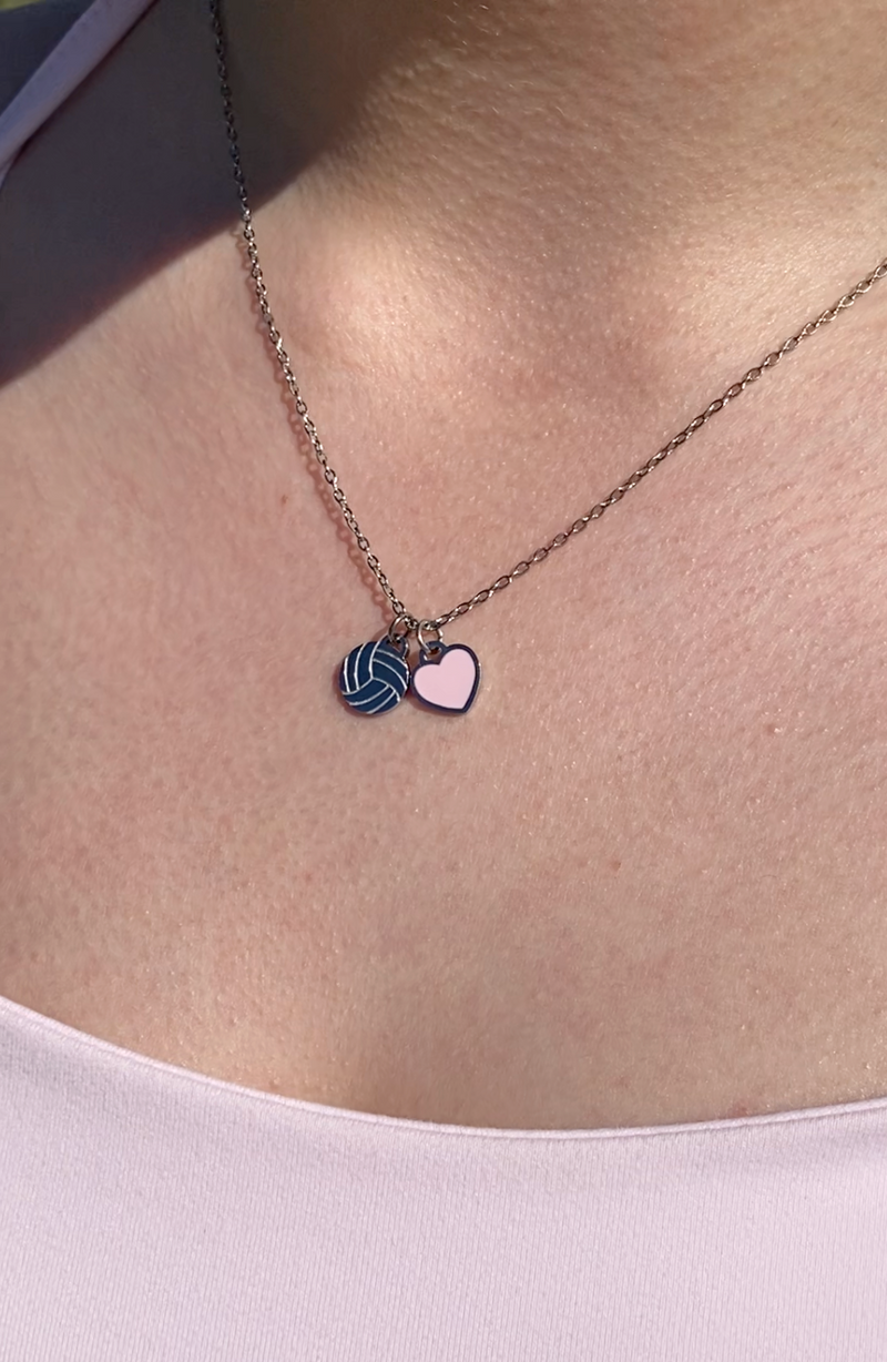 Silver Love of the Game sports ball necklace worn on model with pink heart charm