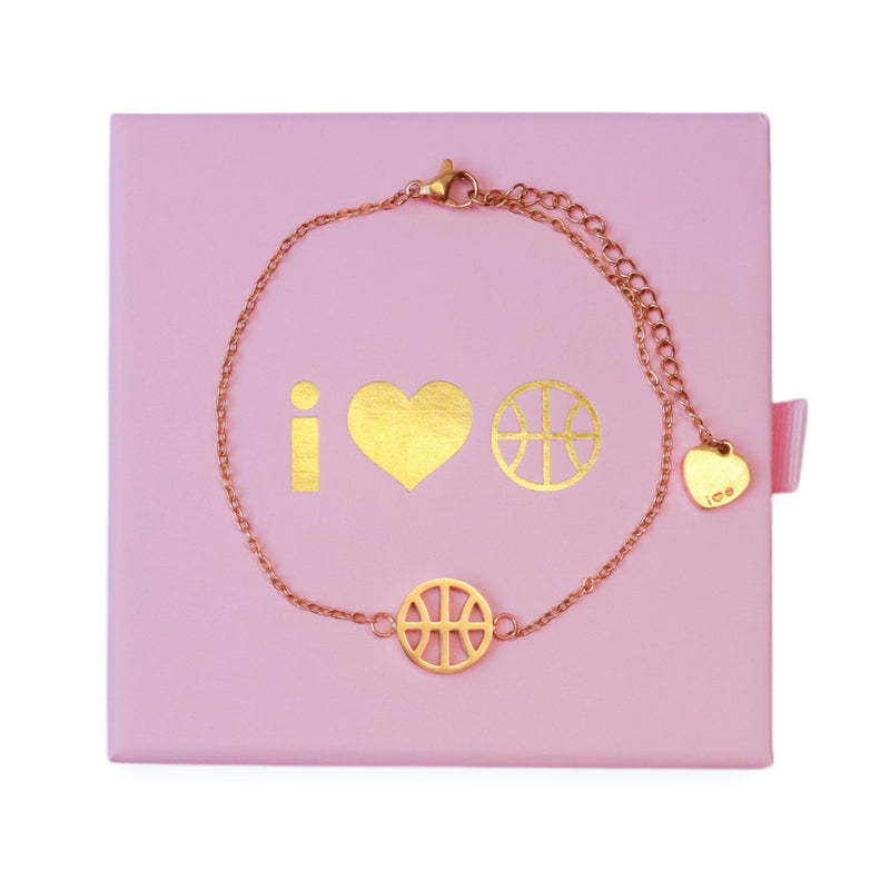 Gold adjustable bracelet with basketball charm and heart charm on the end of the extender chain, displayed on pink I Heart Hoops jewellery box